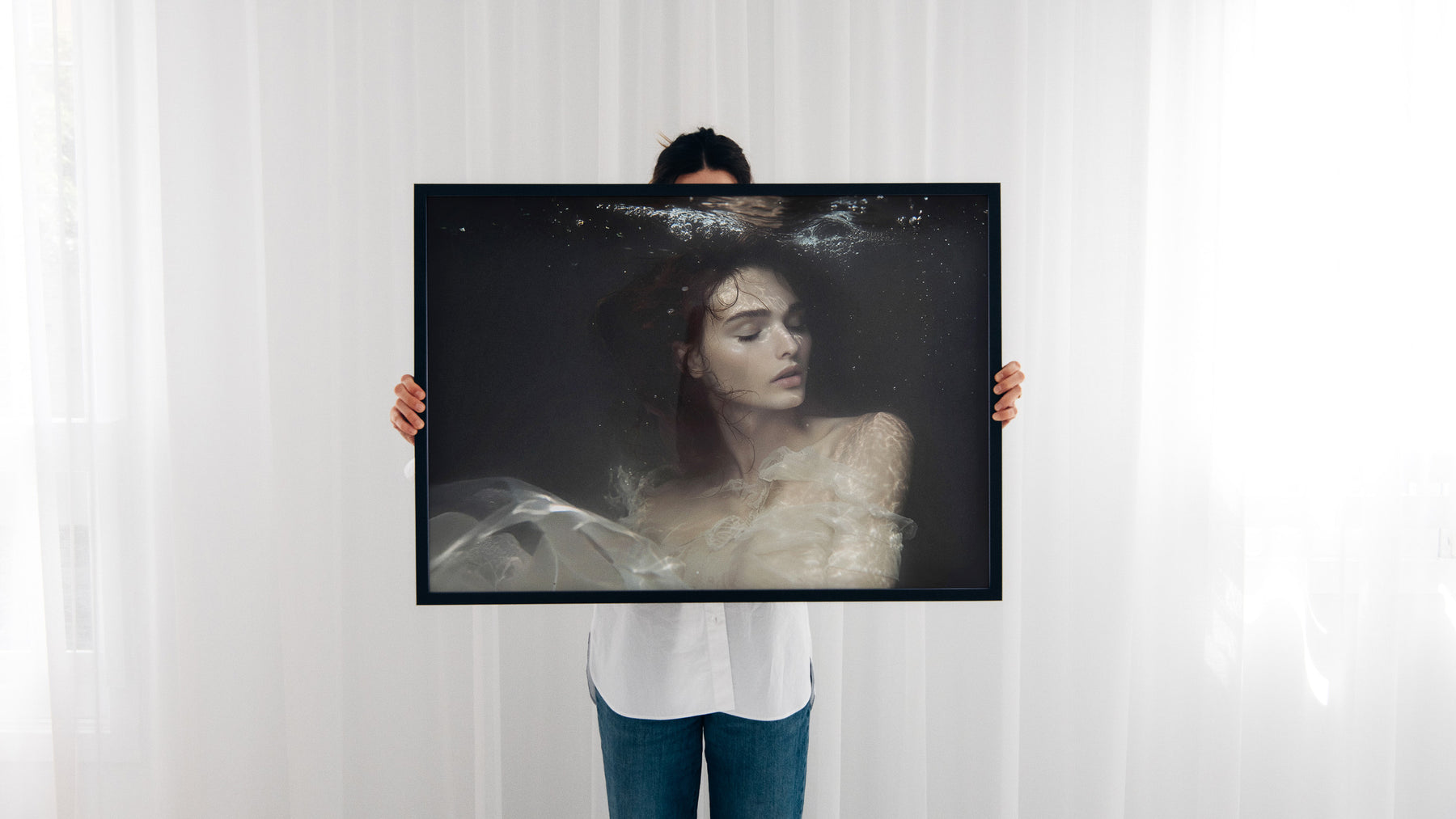 A framed print held in front of white curtains